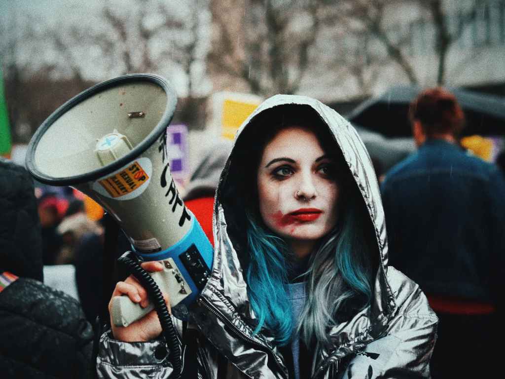 eccentric young lady with loudspeaker during action on street